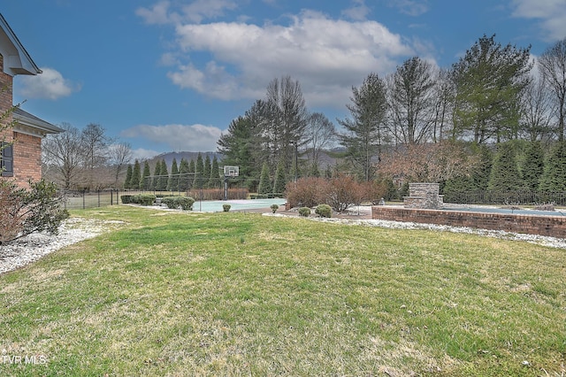 view of yard with basketball court, a mountain view, and fence