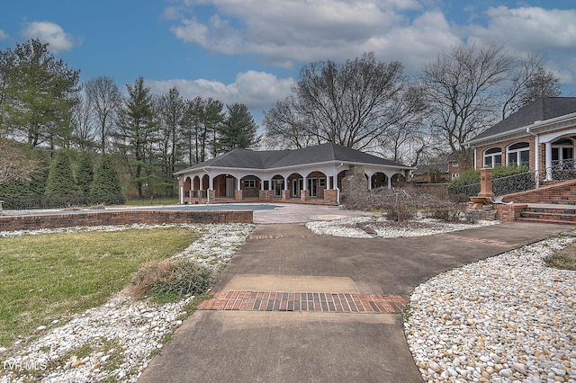 view of front of home featuring aphalt driveway, brick siding, and a front yard