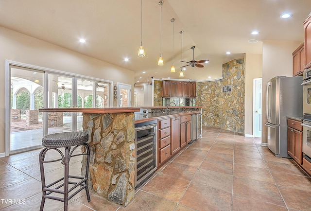 kitchen featuring lofted ceiling, stainless steel appliances, ceiling fan, wine cooler, and a kitchen breakfast bar