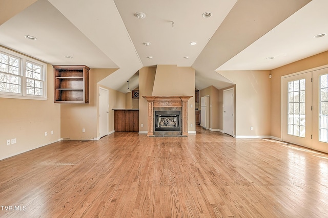 unfurnished living room featuring light wood finished floors, baseboards, vaulted ceiling, recessed lighting, and a fireplace