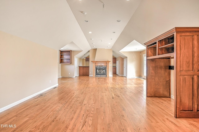 unfurnished living room featuring vaulted ceiling, baseboards, light wood-type flooring, and a tile fireplace