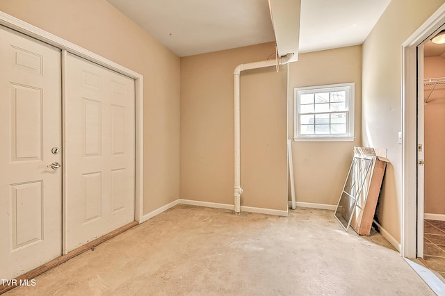 unfurnished bedroom with unfinished concrete flooring and baseboards