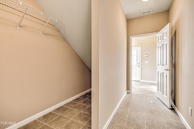 corridor featuring visible vents, baseboards, and tile patterned flooring