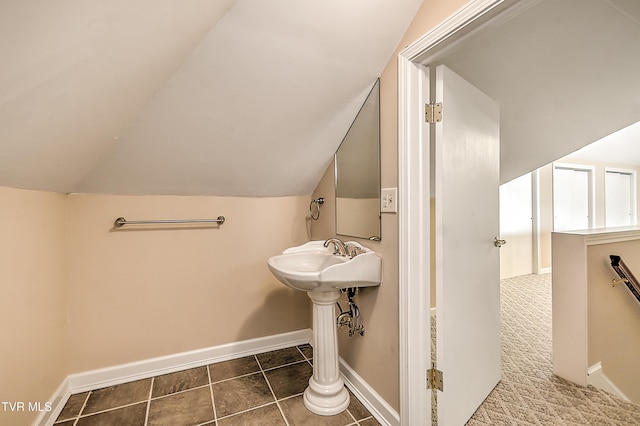 bathroom featuring a sink, baseboards, vaulted ceiling, and tile patterned flooring