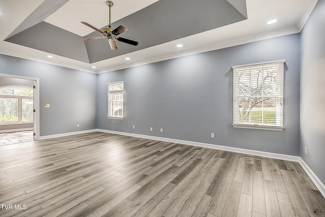 spare room featuring crown molding, a raised ceiling, a ceiling fan, and wood finished floors