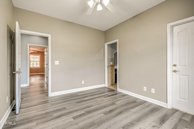 unfurnished bedroom with light wood finished floors, a ceiling fan, and baseboards