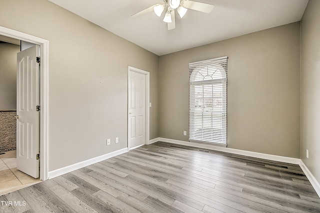 empty room with light wood-type flooring, baseboards, and a ceiling fan