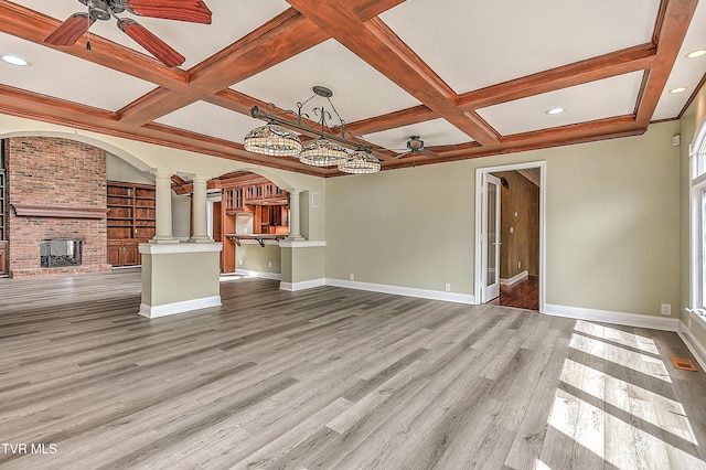 unfurnished living room with light wood-type flooring, decorative columns, ceiling fan, and a fireplace