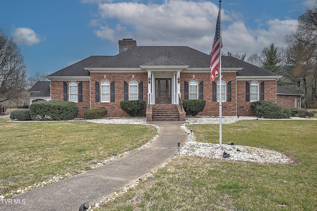 view of front of house with brick siding, a chimney, and a front lawn