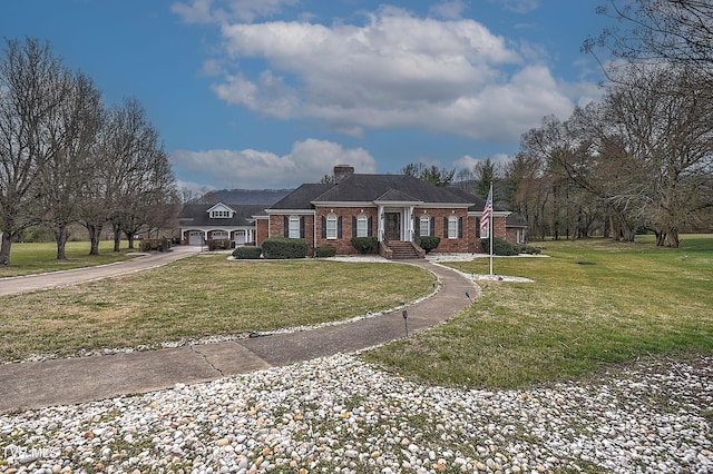 view of front of home featuring a front yard, brick siding, driveway, and a chimney