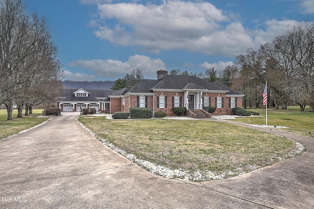 view of front facade with a front yard, driveway, a chimney, a garage, and brick siding