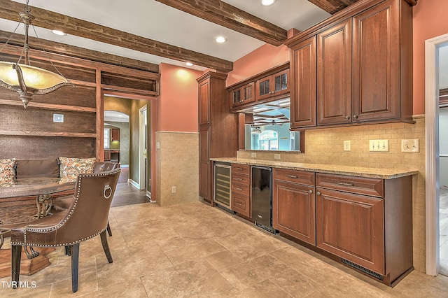 kitchen with beamed ceiling, light stone countertops, arched walkways, and beverage cooler