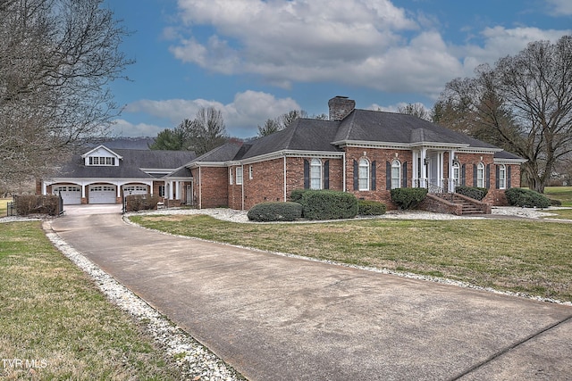 view of front of home featuring a chimney, a front lawn, a garage, aphalt driveway, and brick siding