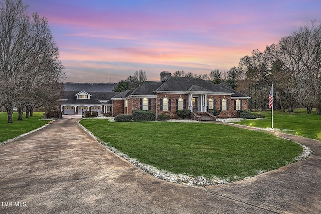 view of front facade featuring brick siding, a front lawn, a garage, an outbuilding, and driveway