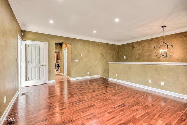 empty room featuring wood finished floors, visible vents, arched walkways, crown molding, and a chandelier