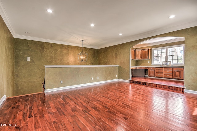 interior space with dark wood finished floors, crown molding, baseboards, and arched walkways