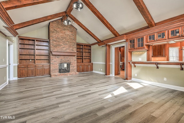 unfurnished living room with a brick fireplace, vaulted ceiling with beams, light wood-style floors, and baseboards