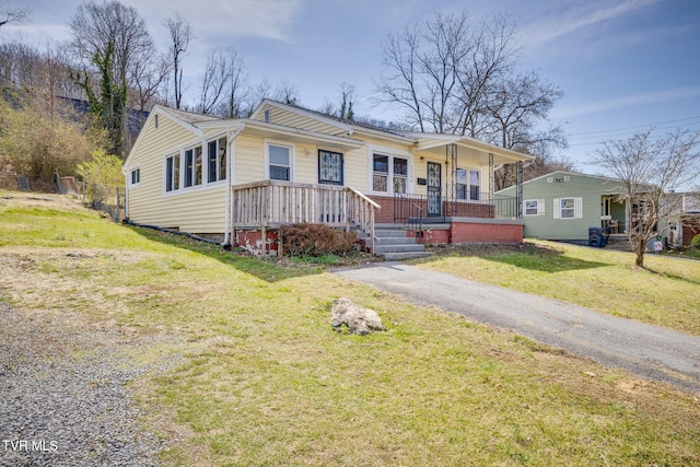 bungalow-style house with brick siding, a porch, driveway, and a front lawn