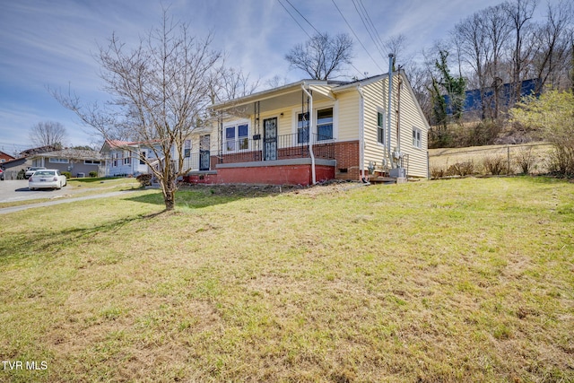 bungalow with a porch, brick siding, a front lawn, and crawl space