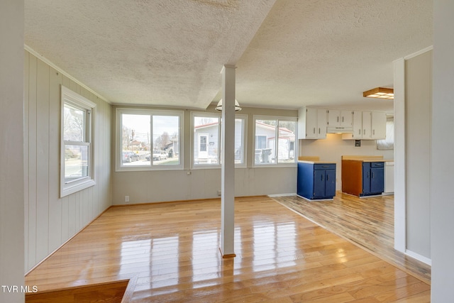 unfurnished living room with crown molding, light wood-style floors, and a textured ceiling