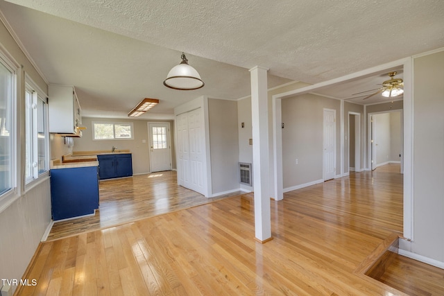 interior space featuring open floor plan, light wood-style flooring, blue cabinetry, and a textured ceiling