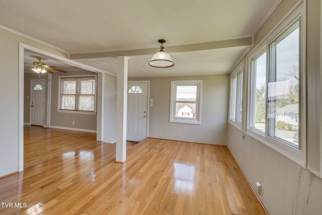 entrance foyer with crown molding, light wood-style flooring, and a textured ceiling