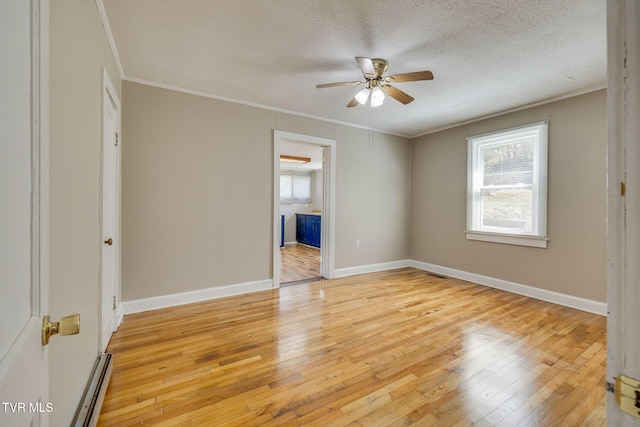 empty room with baseboards, a textured ceiling, light wood-style flooring, and ornamental molding