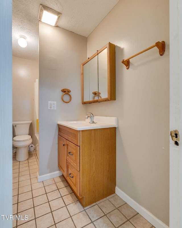 bathroom with vanity, toilet, baseboards, and a textured ceiling