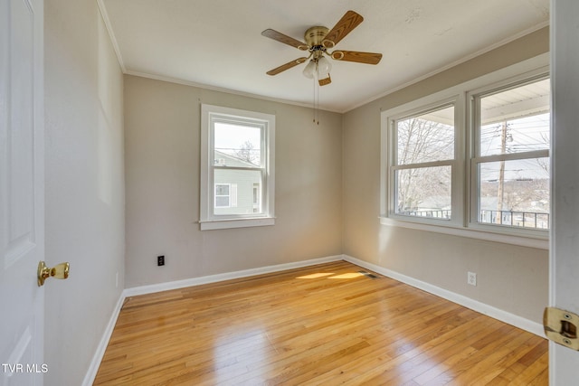 spare room featuring baseboards, crown molding, and light wood finished floors