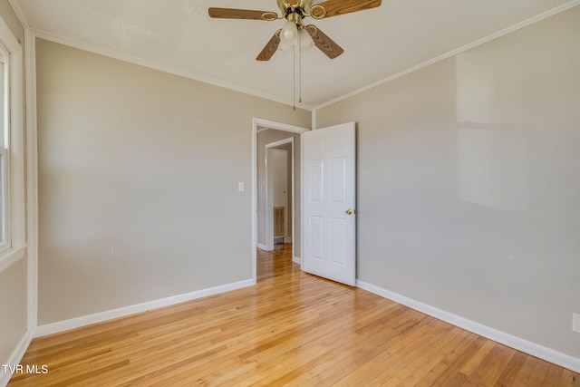 spare room featuring a ceiling fan, crown molding, light wood-style floors, and baseboards