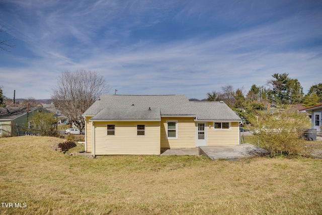 rear view of property with fence, a patio area, a lawn, and roof with shingles