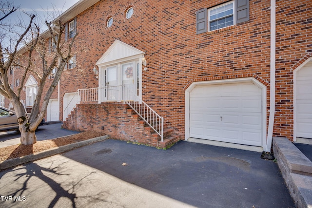 property entrance with brick siding, driveway, and a garage