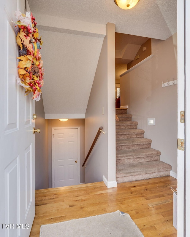 staircase with baseboards, a textured ceiling, and wood finished floors