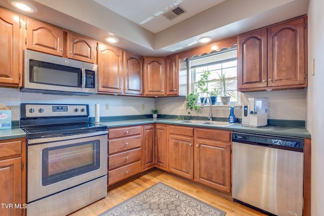 kitchen featuring visible vents, brown cabinets, appliances with stainless steel finishes, and a sink