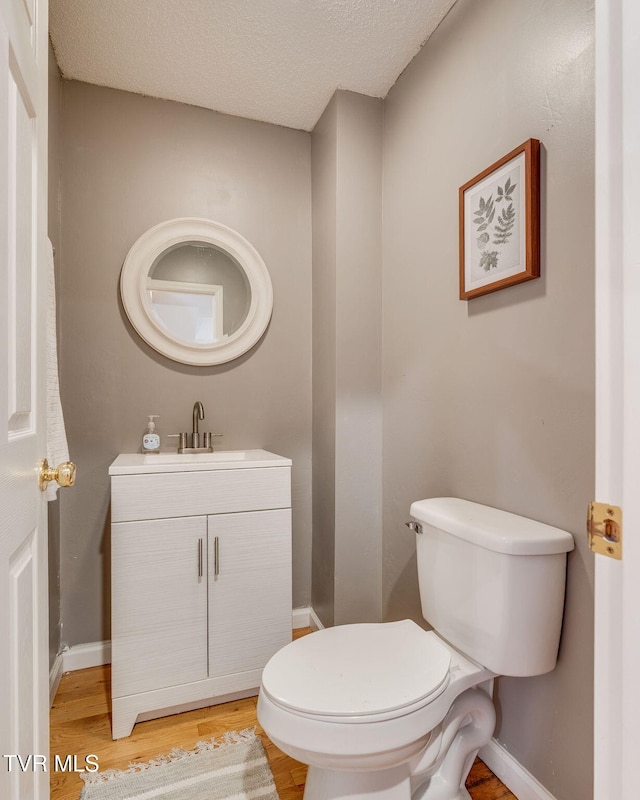 bathroom featuring toilet, vanity, baseboards, and wood finished floors