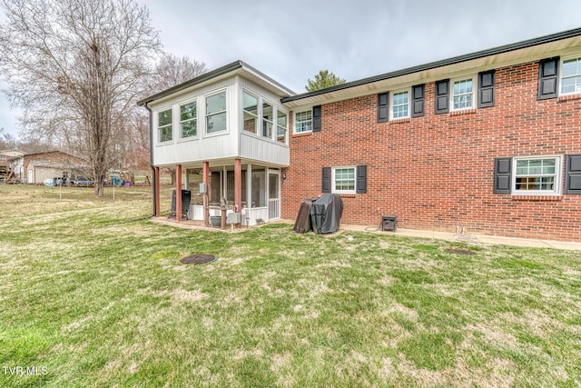 back of property featuring a lawn and brick siding