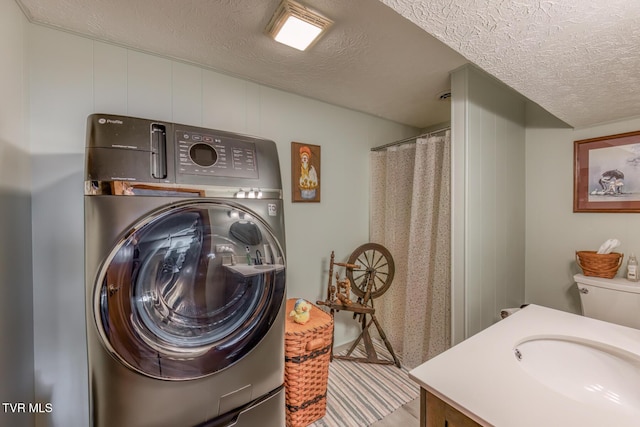 washroom with a sink, washer / clothes dryer, a textured ceiling, and laundry area