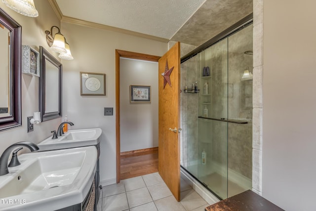 full bathroom featuring tile patterned flooring, crown molding, a stall shower, and a sink