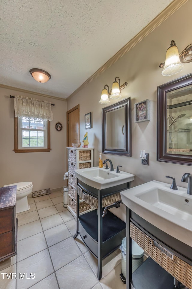 bathroom featuring toilet, two vanities, ornamental molding, a textured ceiling, and tile patterned flooring