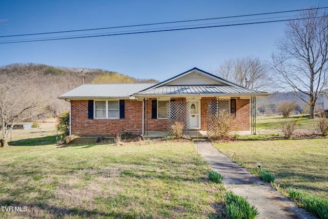 view of front of property featuring brick siding, a porch, metal roof, and a front lawn