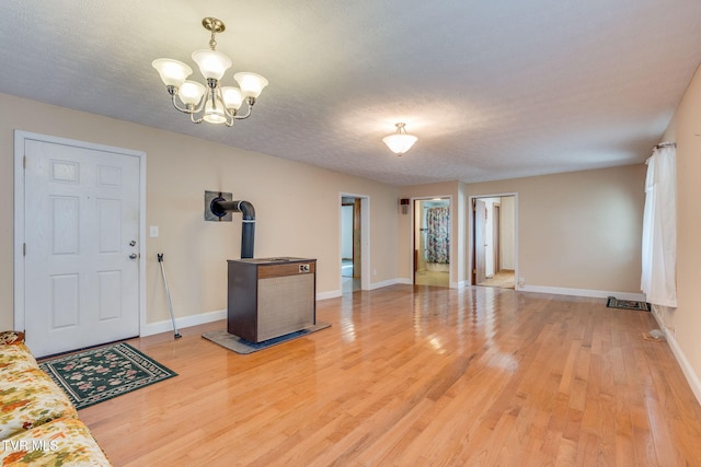 entryway featuring light wood finished floors, baseboards, a wood stove, and an inviting chandelier