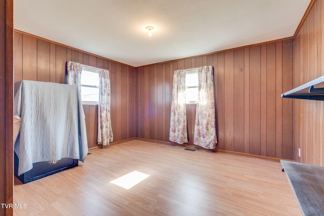 spare room with plenty of natural light, wood finished floors, visible vents, and wood walls