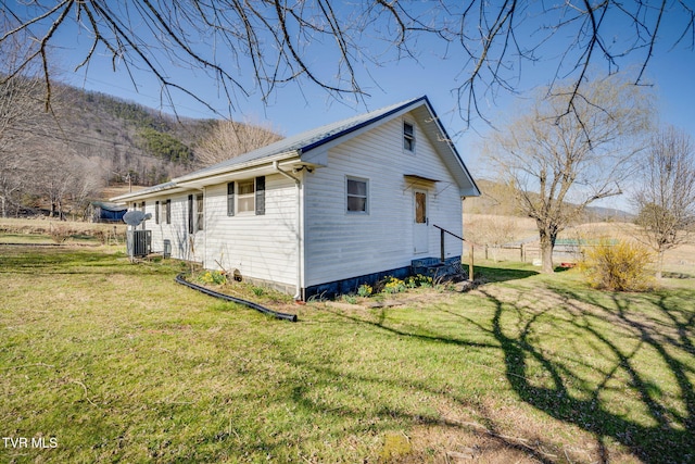 view of side of home with central AC unit, metal roof, and a yard