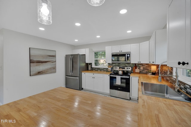 kitchen with a sink, decorative backsplash, wooden counters, and appliances with stainless steel finishes