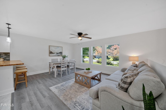 living room featuring ceiling fan, baseboards, and wood finished floors