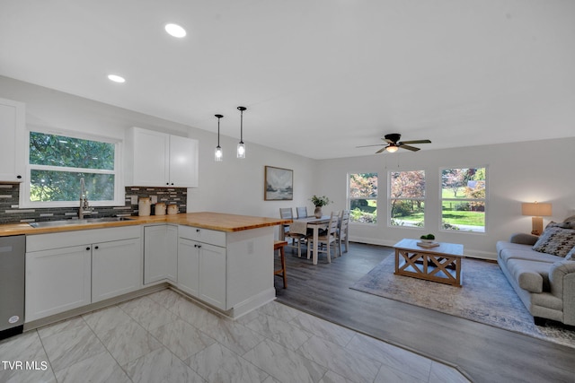 kitchen with open floor plan, wooden counters, decorative backsplash, and a sink