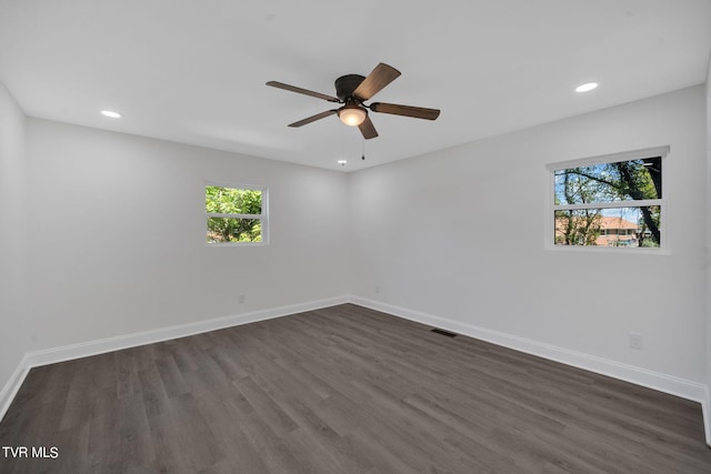 spare room with visible vents, baseboards, and dark wood-style flooring