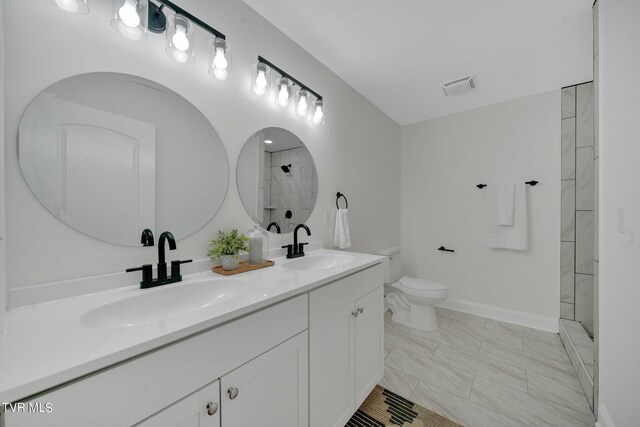 full bathroom featuring toilet, visible vents, a tile shower, and a sink