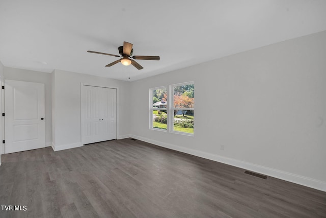 unfurnished bedroom featuring visible vents, ceiling fan, baseboards, a closet, and dark wood-style floors