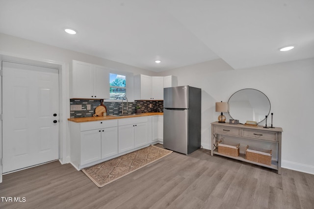 kitchen featuring butcher block countertops, light wood-style flooring, a sink, white cabinetry, and freestanding refrigerator